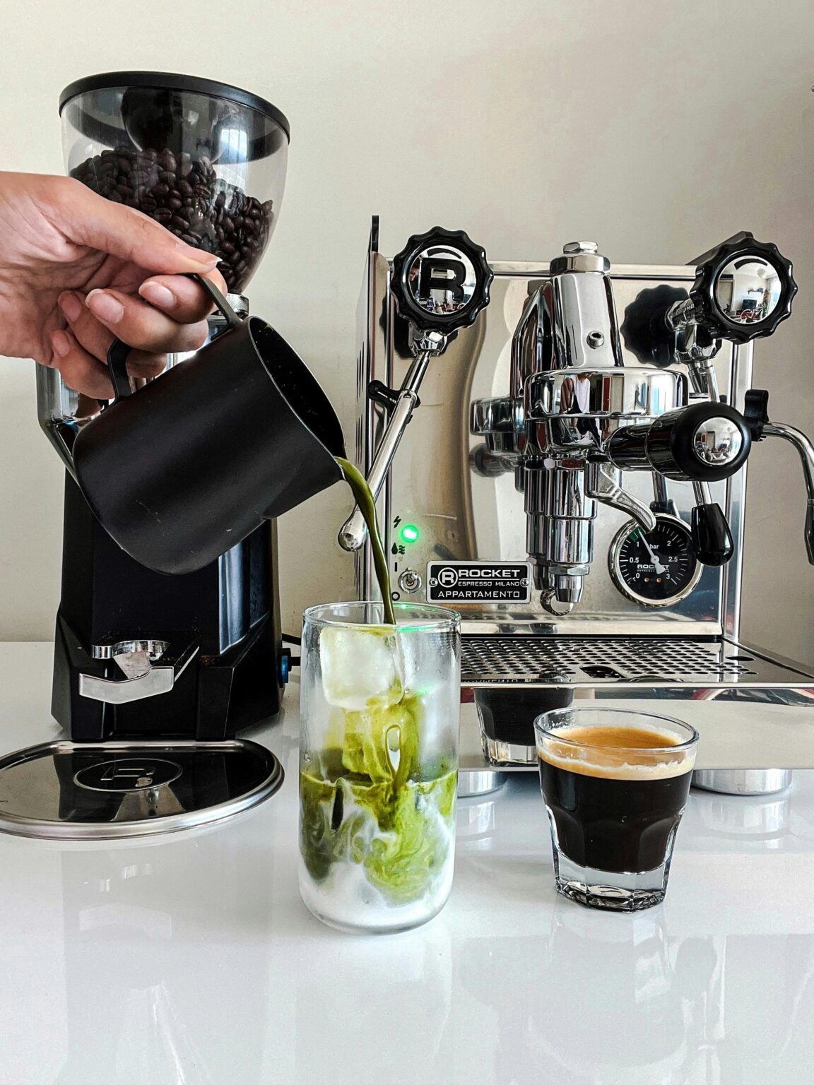 Matcha preparado en la barra de una cafetería junto a la máquina de espresso